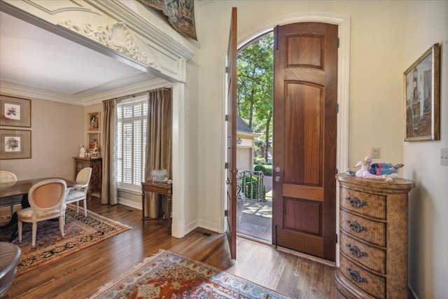 entryway with ornamental molding, wood-type flooring, and a healthy amount of sunlight