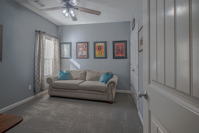 living room featuring ceiling fan, dark carpet, and a textured ceiling