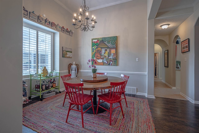 dining area with crown molding, dark wood-type flooring, a textured ceiling, and a notable chandelier