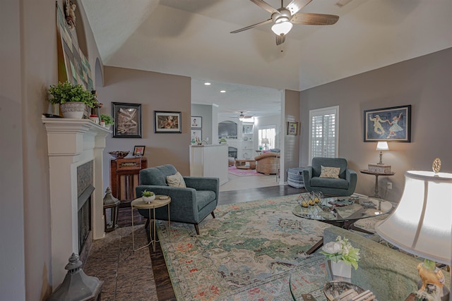 living room featuring ceiling fan, a fireplace, and vaulted ceiling