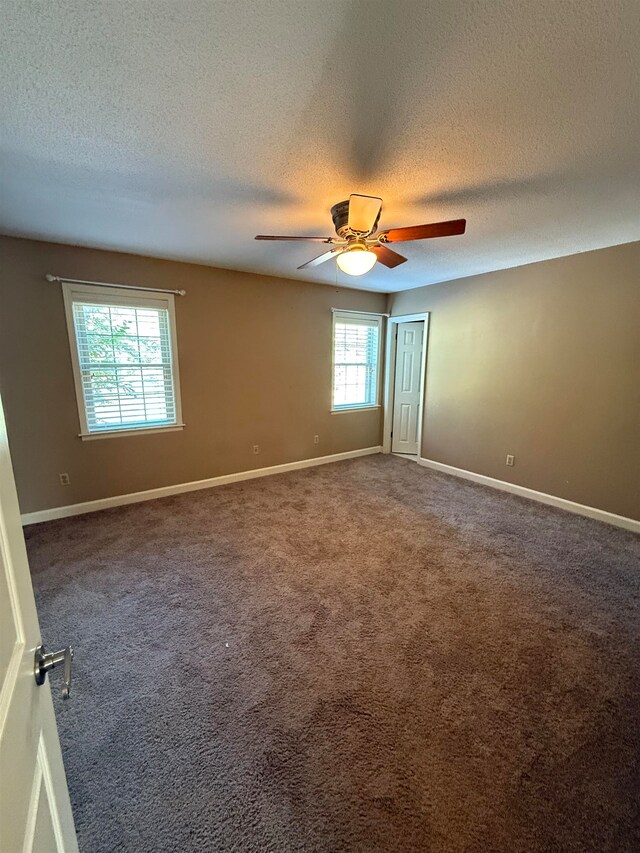 spare room featuring a textured ceiling, carpet floors, ceiling fan, and a wealth of natural light