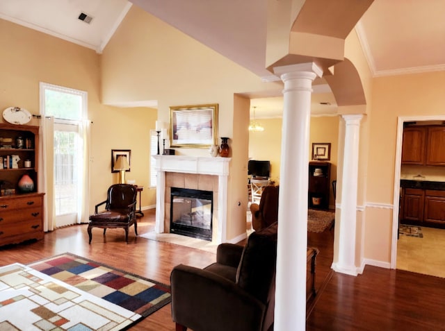 living room with high vaulted ceiling, decorative columns, wood-type flooring, and a tile fireplace