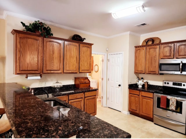 kitchen featuring appliances with stainless steel finishes, ornamental molding, dark stone countertops, and sink