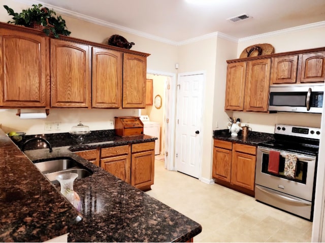 kitchen featuring washer / clothes dryer, appliances with stainless steel finishes, dark stone counters, ornamental molding, and sink