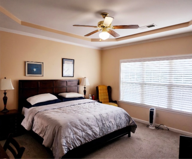 carpeted bedroom with crown molding, a tray ceiling, and ceiling fan