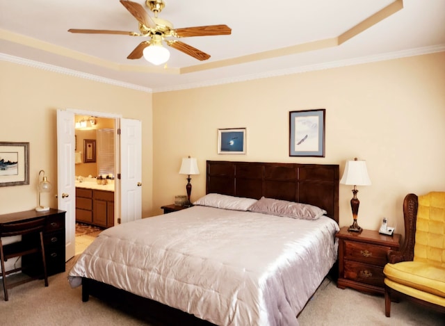 bedroom with connected bathroom, light colored carpet, a tray ceiling, and ceiling fan