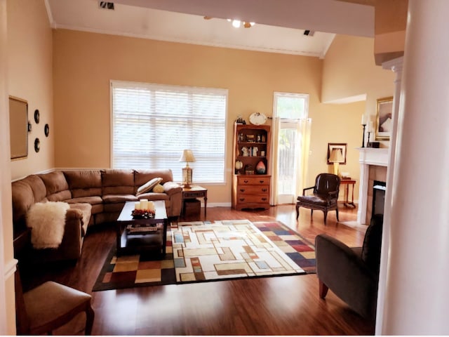 living room featuring beamed ceiling, crown molding, hardwood / wood-style flooring, and a tiled fireplace