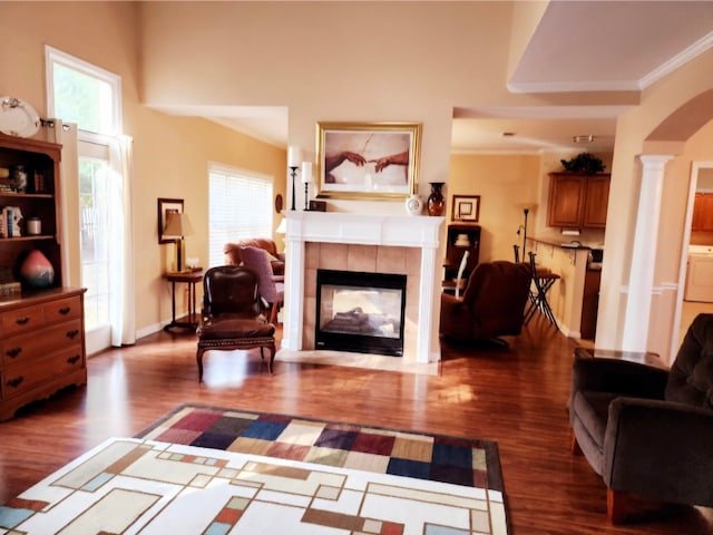 living room featuring ornate columns, a healthy amount of sunlight, a tile fireplace, and dark hardwood / wood-style floors