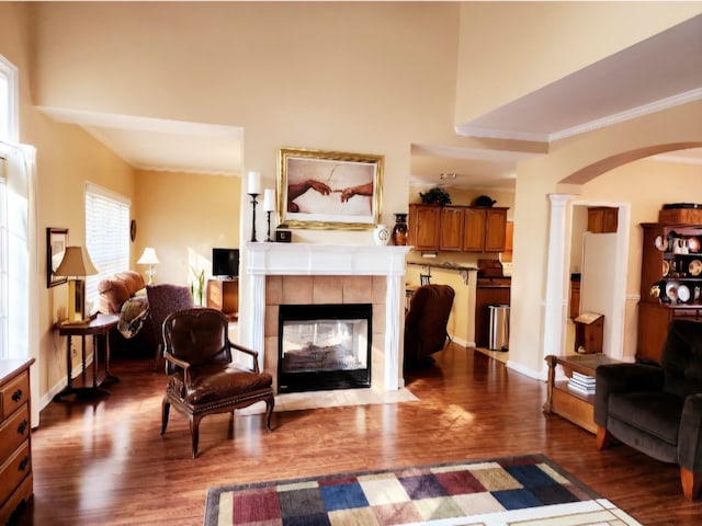 living room featuring dark wood-type flooring, a tile fireplace, and decorative columns