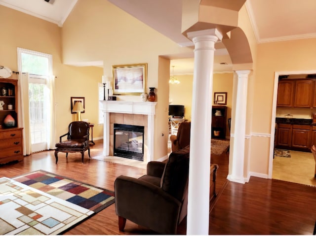 living room with light wood-type flooring, a fireplace, decorative columns, high vaulted ceiling, and ornamental molding