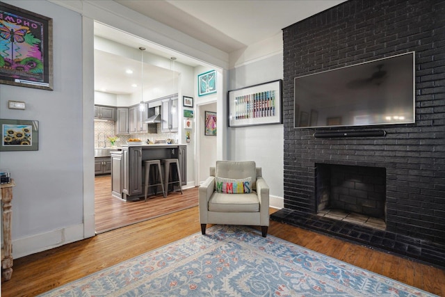 living room featuring hardwood / wood-style floors and a brick fireplace