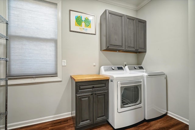 laundry area with dark wood-type flooring, ornamental molding, cabinets, and washer and clothes dryer