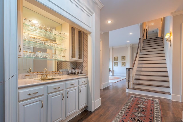 bar with ornamental molding, sink, tasteful backsplash, white cabinetry, and dark hardwood / wood-style flooring