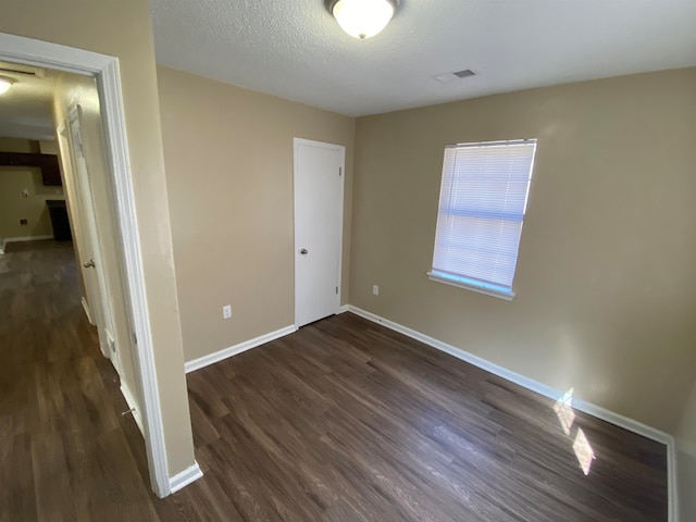 empty room featuring dark wood-type flooring and a textured ceiling