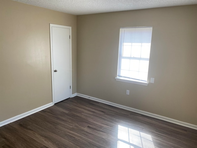 unfurnished room featuring dark wood-type flooring and a textured ceiling