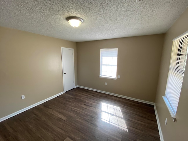 spare room featuring a textured ceiling and dark wood-type flooring