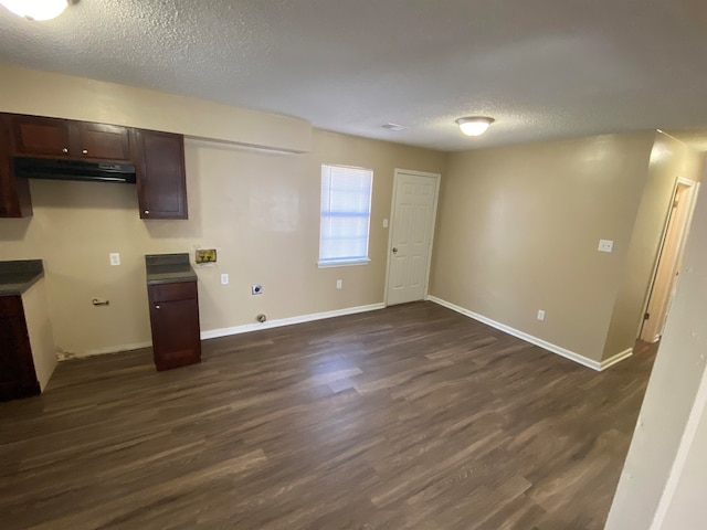 kitchen with dark wood-type flooring, dark brown cabinets, a textured ceiling, and exhaust hood