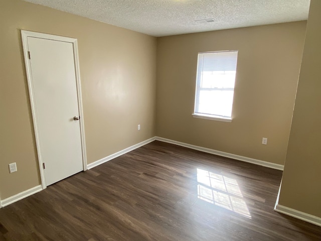 empty room featuring a textured ceiling and dark hardwood / wood-style floors