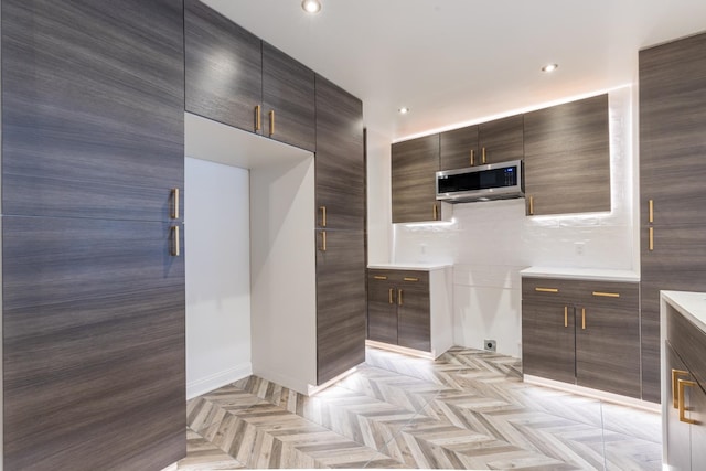 kitchen featuring dark brown cabinets, light parquet floors, and tasteful backsplash