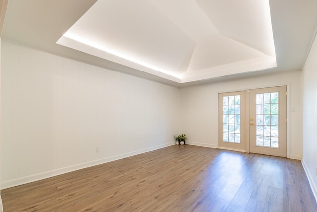 spare room with french doors, hardwood / wood-style flooring, and a tray ceiling