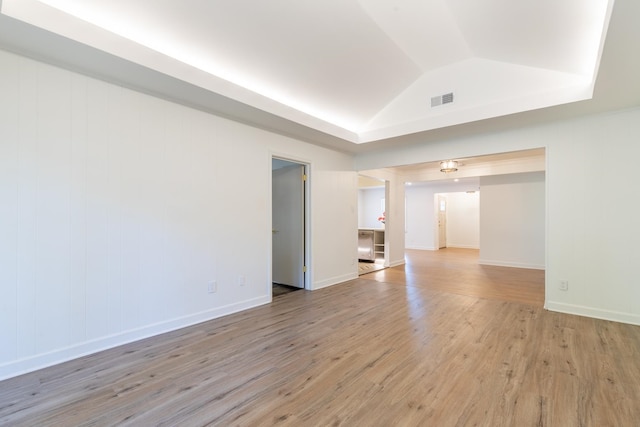 empty room featuring light wood-type flooring and vaulted ceiling