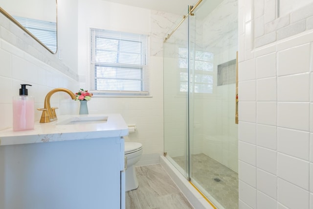 bathroom with tile walls, vanity, toilet, and walk in shower