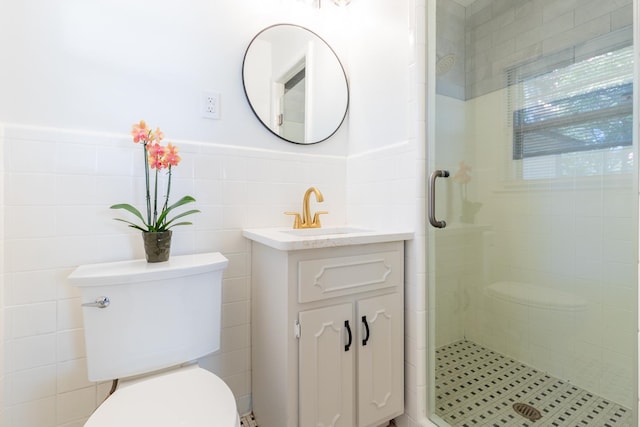 bathroom featuring toilet, a shower with shower door, vanity, and tile walls