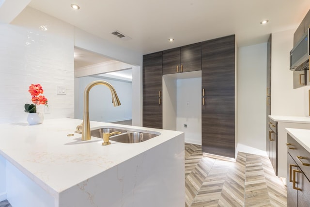 kitchen featuring light stone counters, light parquet flooring, and sink