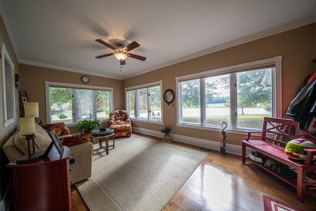 living room featuring ceiling fan, a healthy amount of sunlight, wood-type flooring, and ornamental molding