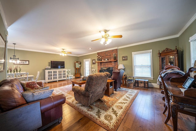 living room with crown molding, dark wood-type flooring, a brick fireplace, and ceiling fan