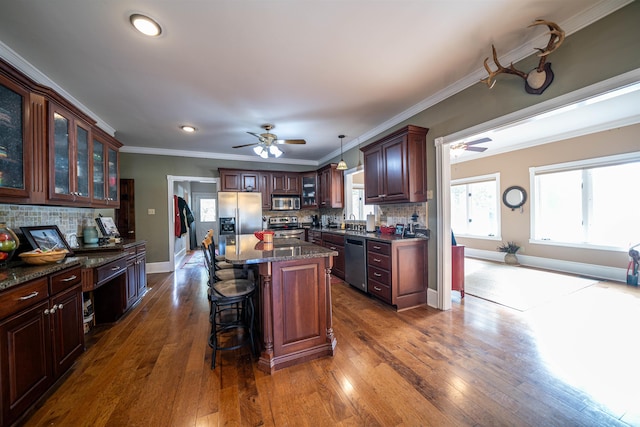 kitchen with tasteful backsplash, dark hardwood / wood-style floors, stainless steel appliances, pendant lighting, and a center island