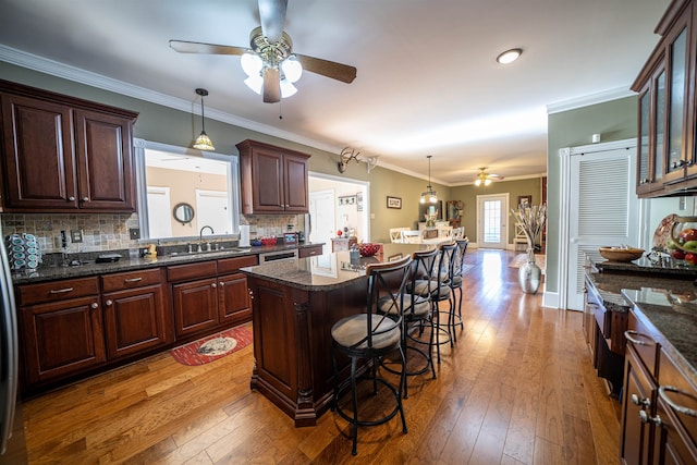 kitchen featuring crown molding, a breakfast bar area, pendant lighting, and hardwood / wood-style floors