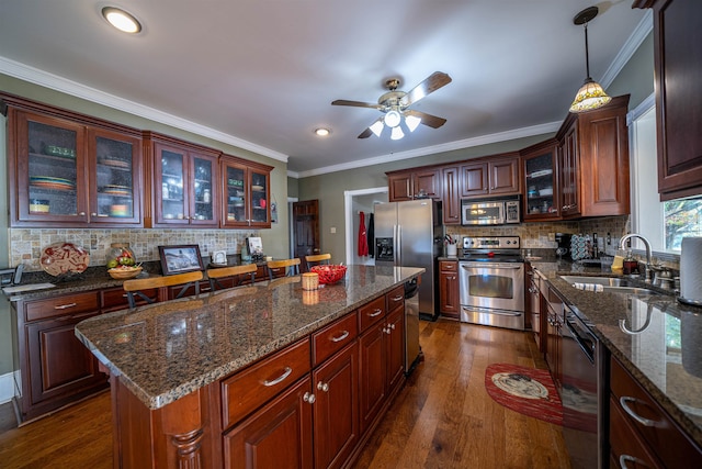 kitchen with hanging light fixtures, dark hardwood / wood-style flooring, a kitchen island, sink, and stainless steel appliances