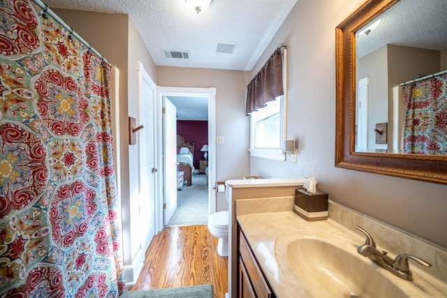 bathroom with vanity, a textured ceiling, hardwood / wood-style flooring, and toilet