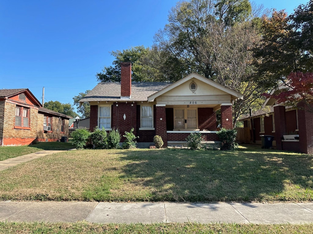 view of front of home with covered porch and a front lawn