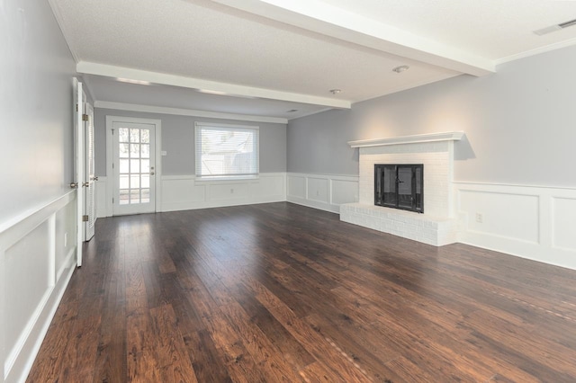 unfurnished living room featuring crown molding, beam ceiling, a fireplace, and dark hardwood / wood-style flooring