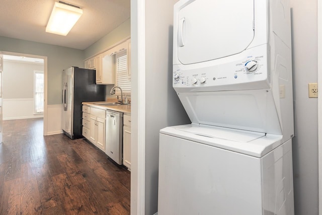 laundry room featuring dark wood-type flooring, stacked washer and dryer, sink, and a textured ceiling