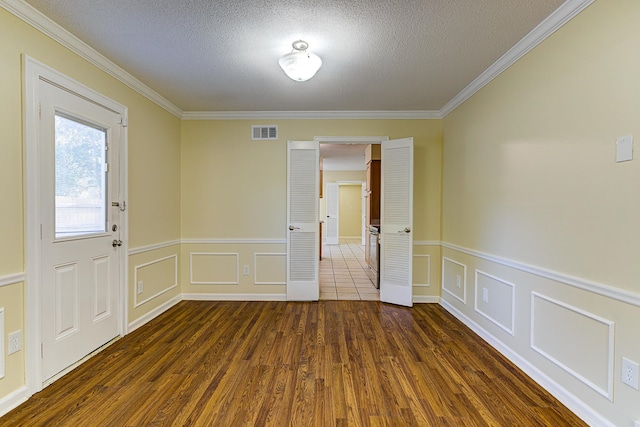 spare room with ornamental molding, a textured ceiling, and dark wood-type flooring