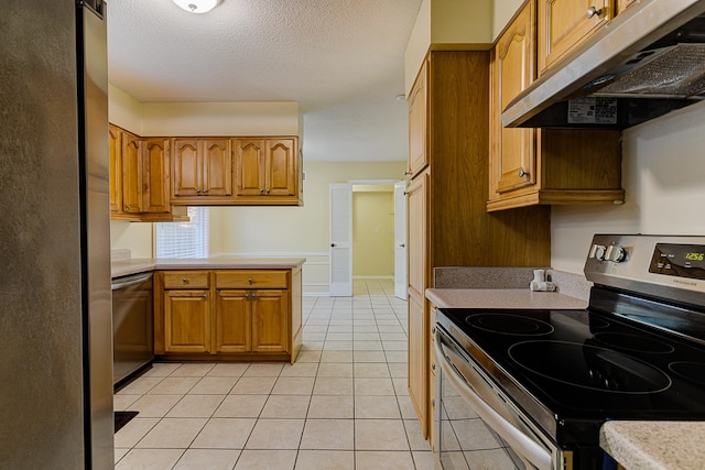 kitchen featuring appliances with stainless steel finishes, kitchen peninsula, a textured ceiling, and light tile patterned flooring