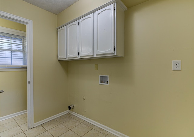 washroom with hookup for a washing machine, a textured ceiling, light tile patterned floors, and cabinets