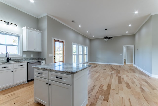 kitchen featuring a wealth of natural light, sink, stainless steel dishwasher, and white cabinets