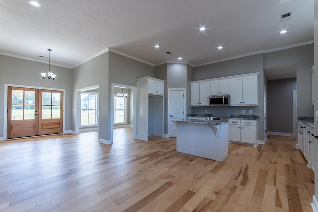 kitchen with white cabinetry, light wood-type flooring, and a kitchen island