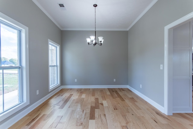 empty room featuring crown molding, a notable chandelier, and light hardwood / wood-style flooring