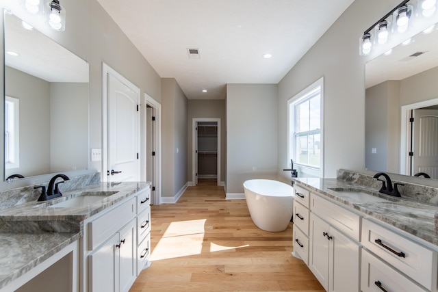 bathroom featuring vanity, a tub, and wood-type flooring