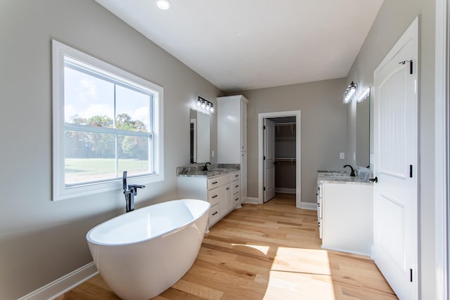 bathroom with vanity, wood-type flooring, and a bath