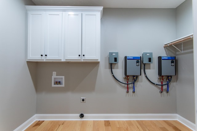 laundry area featuring hookup for an electric dryer, washer hookup, light wood-type flooring, and cabinets