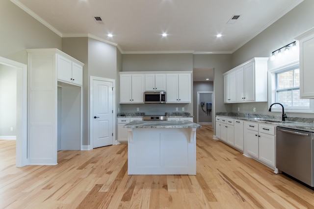 kitchen with light hardwood / wood-style floors, appliances with stainless steel finishes, sink, and a kitchen island