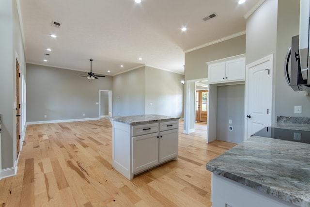 kitchen with light stone counters, white cabinets, and light hardwood / wood-style flooring