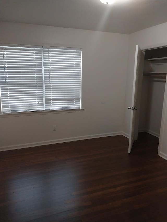 unfurnished bedroom with a closet and dark hardwood / wood-style flooring