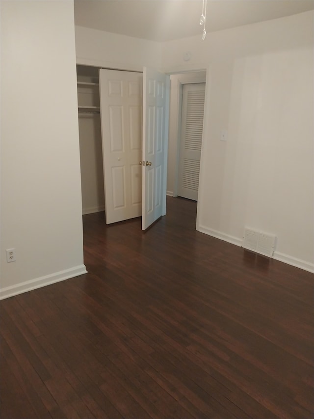 unfurnished bedroom featuring dark wood-type flooring and a closet